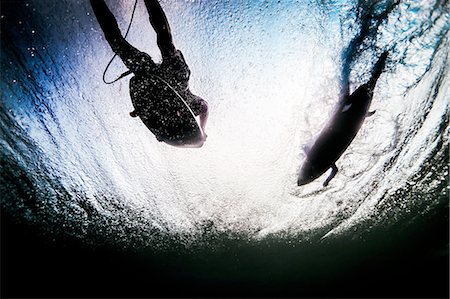 person underwater looking up - Low angle underwater view of two silhouetted surfers paddling through ocean waves in Bali, Indonesia Stock Photo - Premium Royalty-Free, Code: 649-08237637