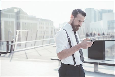 Businessman reading smartphone update on footbridge Stock Photo - Premium Royalty-Free, Code: 649-08237675