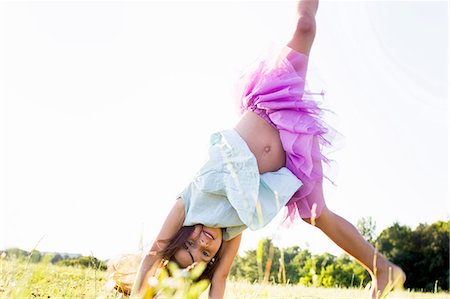 person upside down - Cute girl wearing tutu cartwheeling in park Stock Photo - Premium Royalty-Free, Code: 649-08237806