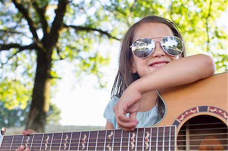 Girl wearing sunglasses posing with acoustic guitar in park Stock Photo - Premium Royalty-Free, Code: 649-08237801