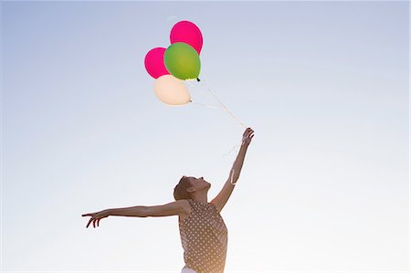simsearch:632-06118588,k - Low angle view of mature woman holding up bunch of balloons against blues sky Stock Photo - Premium Royalty-Free, Code: 649-08237816