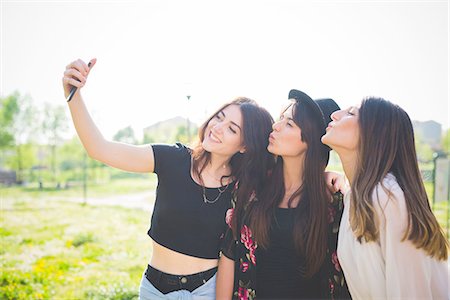 simsearch:649-08307518,k - Three young female friends puckering lips for smartphone selfie in park Foto de stock - Sin royalties Premium, Código: 649-08238001