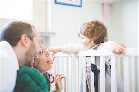 Mid adult couple laughing with toddler daughter in crib Stock Photo - Premium Royalty-Free, Code: 649-08238413