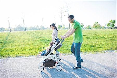 Mid adult couple and toddler daughter in pushchair strolling in park Stock Photo - Premium Royalty-Free, Code: 649-08238444