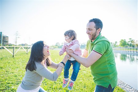 simsearch:649-08238410,k - Mid adult couple handing toddler daughter to each other in park Photographie de stock - Premium Libres de Droits, Code: 649-08238442