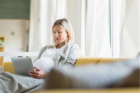 Full term pregnancy young woman on sofa using digital tablet Foto de stock - Sin royalties Premium, Código: 649-08238467