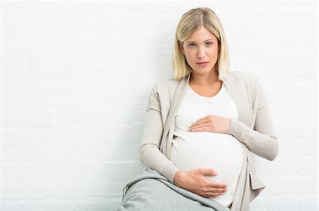 Portrait of full term pregnancy young woman sitting holding stomach Stockbilder - Premium RF Lizenzfrei, Bildnummer: 649-08238472