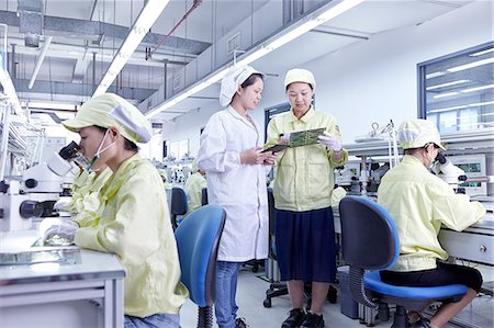 Supervisor overseeing work at quality check station at factory producing flexible electronic circuit boards. Plant is located in the south of China, in Zhuhai, Guangdong province Foto de stock - Sin royalties Premium, Código: 649-08238665