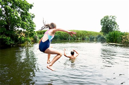 Teenage boy and sister jumping into lake Stock Photo - Premium Royalty-Free, Code: 649-08238764