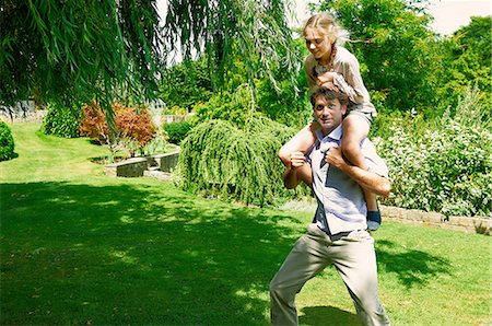 simsearch:649-07436476,k - Mature man running with daughter on his shoulders in garden Fotografie stock - Premium Royalty-Free, Codice: 649-08238779