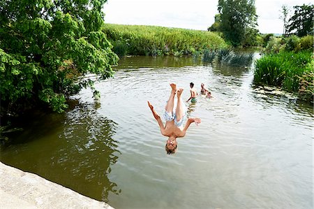 Teenage boy somersaulting into rural lake Stock Photo - Premium Royalty-Free, Code: 649-08238773