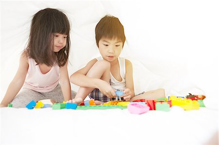 simsearch:640-06963758,k - Young Chinese boy and girl in bed playing with their toys under the bedsheets Foto de stock - Royalty Free Premium, Número: 649-08239016