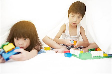 simsearch:640-06963758,k - Young Chinese boy and girl in bed playing with their toys under the bedsheets Foto de stock - Royalty Free Premium, Número: 649-08239017