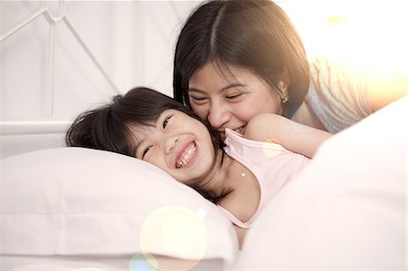 family tickling - Young Chinese mother and daughter laying in bed together at home Stock Photo - Premium Royalty-Free, Code: 649-08239011