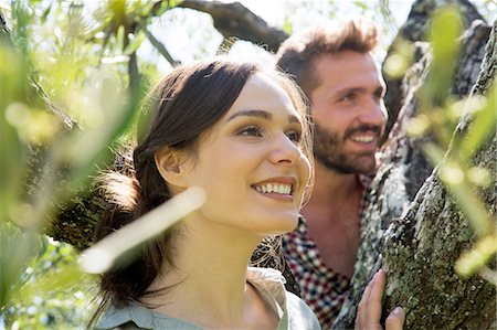 simsearch:649-08239072,k - Young couple in tree looking away smiling Foto de stock - Sin royalties Premium, Código: 649-08239071