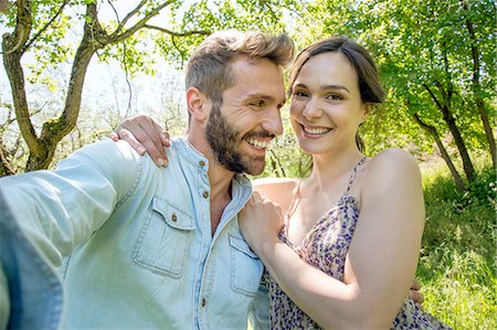 simsearch:649-08239072,k - Young woman with arm around young man looking at camera smiling Foto de stock - Sin royalties Premium, Código: 649-08239087