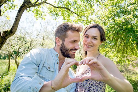 Young couple making heart shape with hands, looking at camera smiling Stock Photo - Premium Royalty-Free, Code: 649-08239088