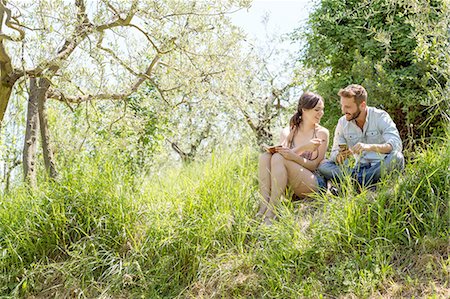 simsearch:649-08239072,k - Low angle view of young couple sitting on hill holding smartphone Foto de stock - Sin royalties Premium, Código: 649-08239094