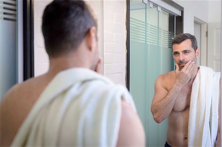 Bare chested mature man looking in mirror, hand on chin, touching stubble, towel over shoulder Stockbilder - Premium RF Lizenzfrei, Bildnummer: 649-08232408