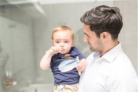 father son bathroom - Father holding young son while son brushes teeth Photographie de stock - Premium Libres de Droits, Code: 649-08232515
