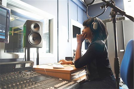 simsearch:694-03694097,k - Side view of young woman wearing headphones, sitting at mixing desk in recording studio looking at monitor Foto de stock - Royalty Free Premium, Número: 649-08232668