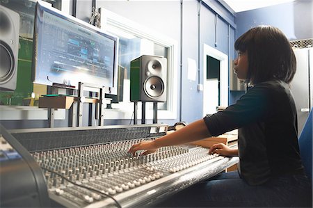 simsearch:694-03694097,k - Side view of young woman sitting at mixing desk in recording studio looking at monitor, adjusting controls Foto de stock - Royalty Free Premium, Número: 649-08232671