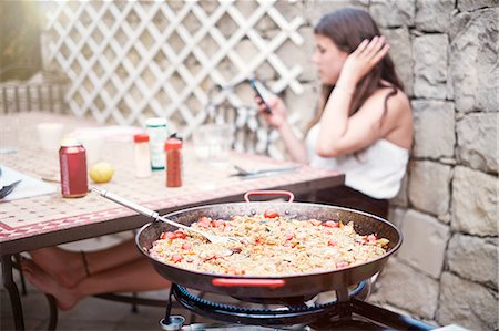 paella - Teenage girl texting on smartphone at patio lunch table Fotografie stock - Premium Royalty-Free, Codice: 649-08232708