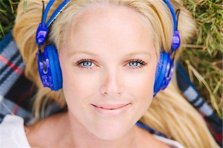 ease - High angle view of young woman wearing headphones lying on blanket looking at camera smiling Stock Photo - Premium Royalty-Free, Code: 649-08232921