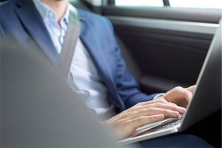 simsearch:614-08877313,k - Young businessman chatting typing on laptop in back seat of car Stock Photo - Premium Royalty-Free, Code: 649-08306369