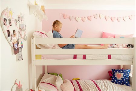 Side view of girl sitting on top bunk of bunkbed reading magazine Foto de stock - Sin royalties Premium, Código: 649-08306392