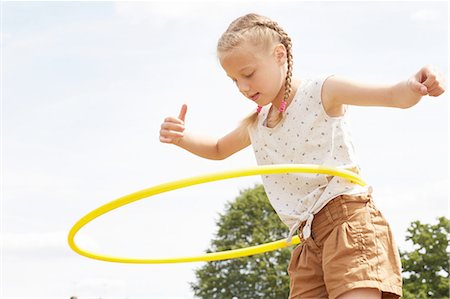 Low angle view of girl using hula hoop, arms open looking down Fotografie stock - Premium Royalty-Free, Codice: 649-08306408