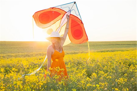 summer fun - Mid adult woman in canola field arm raised holding kite Stock Photo - Premium Royalty-Free, Code: 649-08306676