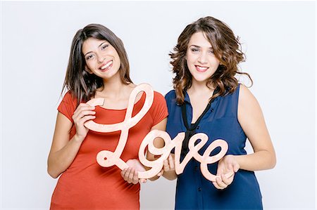 Lesbian couple holding the word love, looking at camera smiling Stock Photo - Premium Royalty-Free, Code: 649-08306684