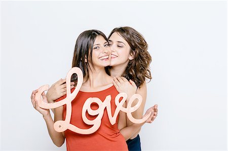 Lesbian couple holding the word love, looking at camera smiling Foto de stock - Sin royalties Premium, Código: 649-08306685