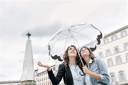 sharing umbrella - Lesbian couple holding umbrella checking for rain with hand, looking up, Piazza Santa Maria Novella, Florence, Tuscany, Italy Stock Photo - Premium Royalty-Free, Code: 649-08306690