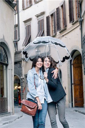 simsearch:649-08306727,k - Lesbian couple standing together in street holding umbrella looking at camera smiling, Florence, Tuscany, Italy Stock Photo - Premium Royalty-Free, Code: 649-08306735