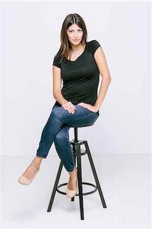 Young woman sitting on stool looking at camera pouting Stock Photo - Premium Royalty-Free, Code: 649-08306744