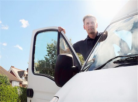 Delivery man looking out from white van on suburban street Foto de stock - Sin royalties Premium, Código: 649-08306955