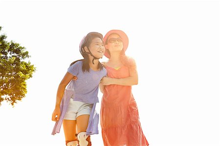 rollerblading female - Woman with arm around rollerblading daughter in sunlight Stock Photo - Premium Royalty-Free, Code: 649-08307178