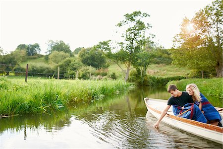 Young man with girlfriend touching water from river  rowing boat Foto de stock - Sin royalties Premium, Código: 649-08307318