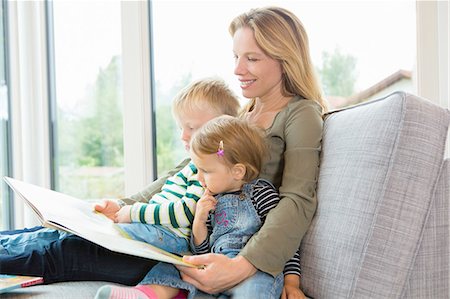 Mother and two young children sitting on sofa reading a book Stock Photo - Premium Royalty-Free, Code: 649-08307440