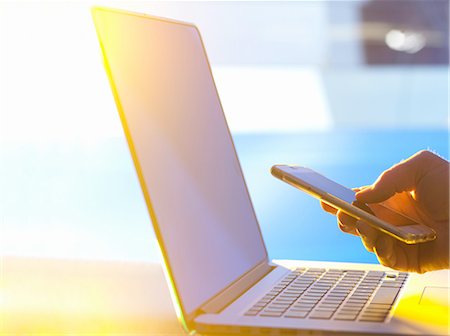 person and mobile phone - Business man at laptop computer with smartphone in office with sunlight coming through window Stock Photo - Premium Royalty-Free, Code: 649-08327664