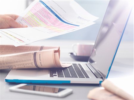 Man reviewing financial affairs using newspaper market data, investment statement and laptop Stock Photo - Premium Royalty-Free, Code: 649-08327683