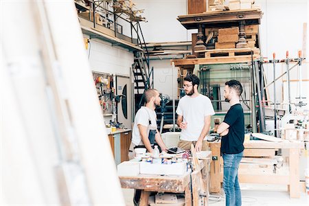 simsearch:649-08329135,k - Friends standing around workbench in carpentry workshop talking Foto de stock - Royalty Free Premium, Número: 649-08327865