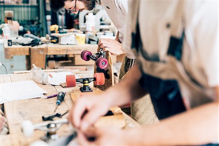 simsearch:649-08329135,k - Young men in carpentry workshop looking down making skateboards Foto de stock - Royalty Free Premium, Número: 649-08327872