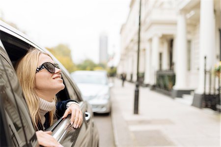 simsearch:649-08328031,k - Young woman wearing sunglasses looking up from car window, London, England, UK Fotografie stock - Premium Royalty-Free, Codice: 649-08328028