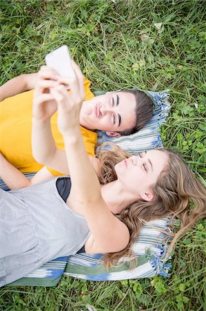 simsearch:649-07585241,k - Young couple lying on grass in field, taking self portrait using smartphone Foto de stock - Sin royalties Premium, Código: 649-08328226