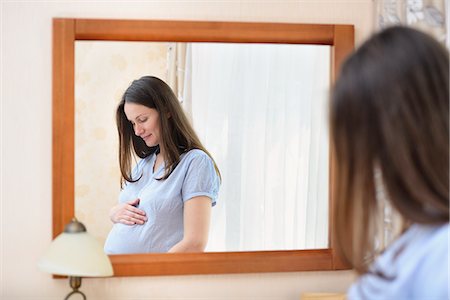 simsearch:614-06624892,k - Pregnant woman holding stomach, standing in front of mirror Stock Photo - Premium Royalty-Free, Code: 649-08328518