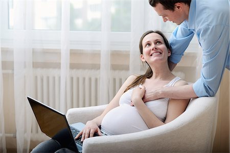standing next to chair - Pregnant woman sitting in chair, using laptop, husband holding her hand Stock Photo - Premium Royalty-Free, Code: 649-08328524