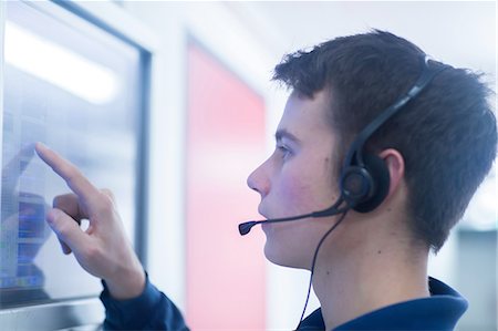 engineer at industry control room - Side view of young man wearing headset using touch screen computer monitor Stock Photo - Premium Royalty-Free, Code: 649-08328777